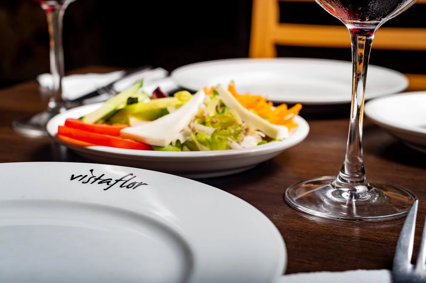 Table dressée avec salade et verre de vin au restaurant Vistaflor